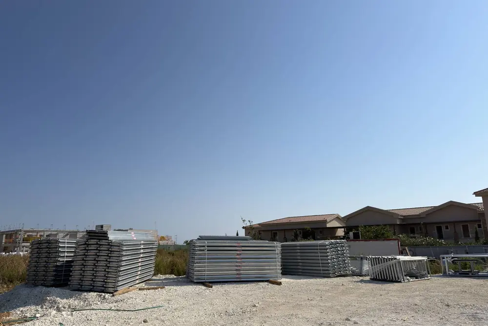 Scaffolding decks and frames stacked in an open yard in Kefalonia